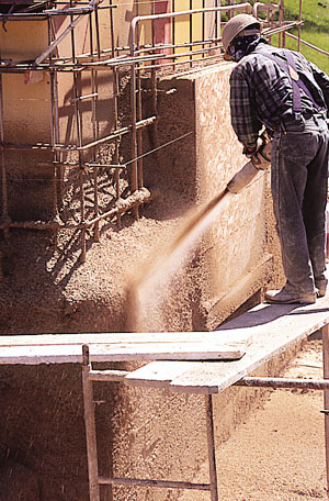 PISE walls are easier, faster, and less costly to erect than rammed-earth walls. Here, high-pressure air shoots a prepared mixture of moistened soil and cement against a one-sided form. Reinforcing steel in the wall eliminates the need for supplemental concrete bond beams. Photo by Cynthia Wright
